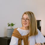 Professional young woman in office wearing glasses, engaging with a notepad.